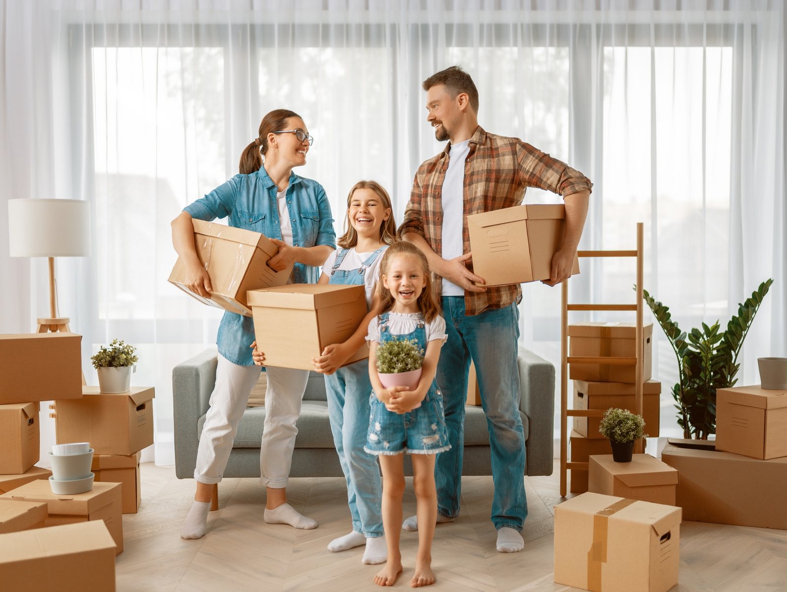A smiling family carrying moving boxes into their new home