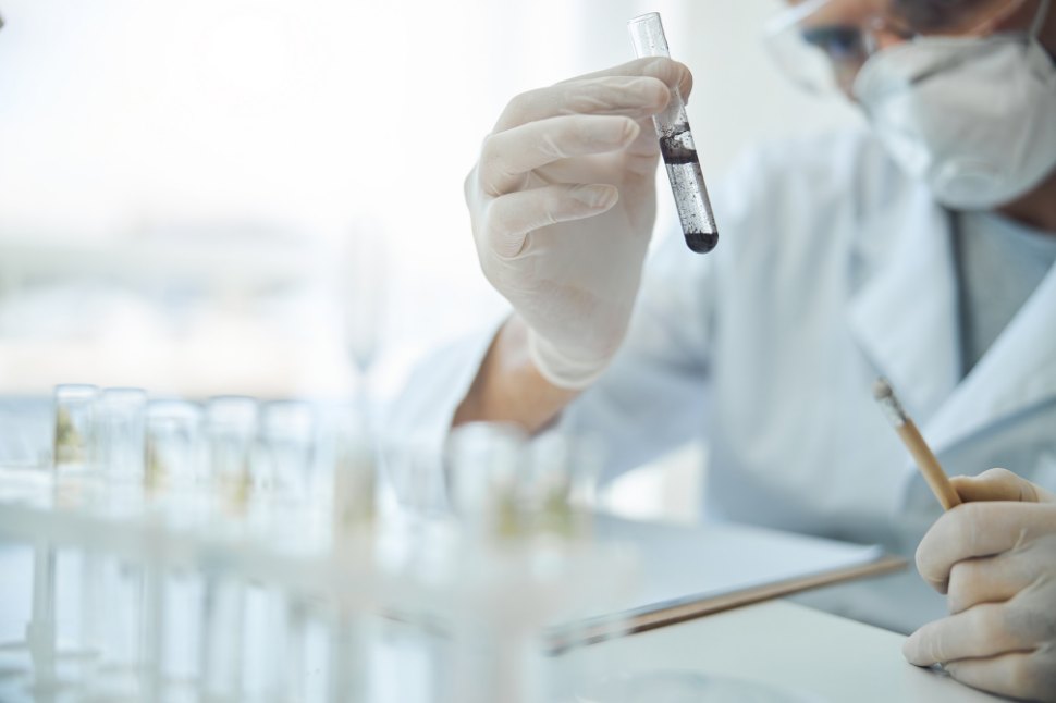 A lab technician holding up a sample vial for analysis